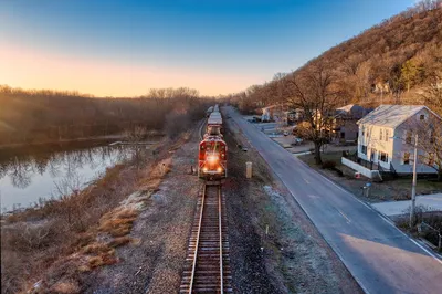 A freight train passing through Reads Landing, MN by the river at sunrise.