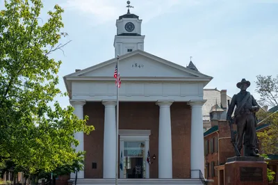 Historic courthouse facade with statue and American flag in daylight.
